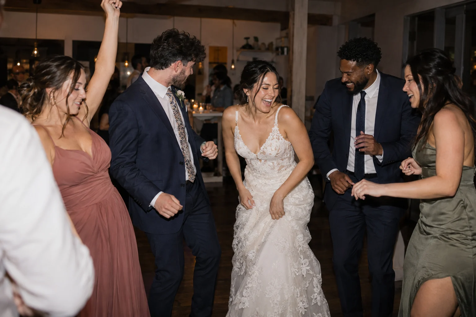 Convidats del casament i una parella recentment casada rient junts a la pista de ball